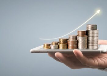 Mão segurando smartphone com pilhas de moedas crescentes e seta ascendente representando crescimento de investimentos