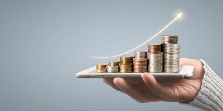 Mão segurando smartphone com pilhas de moedas crescentes e seta ascendente representando crescimento de investimentos