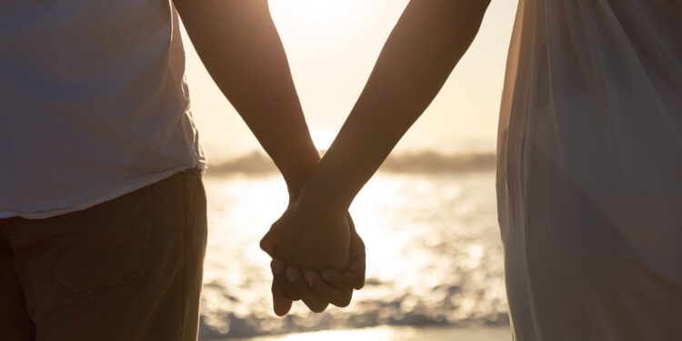 12 Ideias Criativas para Surpreender no Dia dos Namorados 10 casal de mãos dadas na praia - dia dos namorados