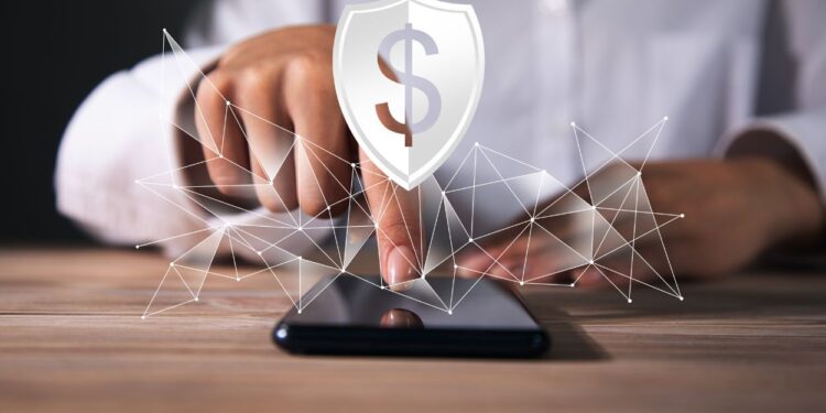 Como Cancelar o Seguro Prestamista: O Guia Definitivo Para Se Livrar da 'Venda Casada' e Recuperar Seu Dinheiro 1 Mão toca smartphone com ícone de escudo e cifrão, representando o direito de cancelar seguro prestamista.