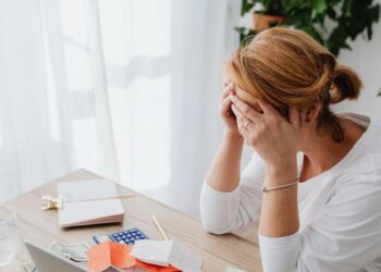 Hoje é 1º de Julho: O Guia de 5 Passos para o seu 'Check-up' Financeiro de Meio de Ano 6 Mulher preocupada com contas e finanças em mesa de escritório.