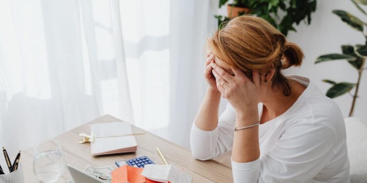 Hoje é 1º de Julho: O Guia de 5 Passos para o seu 'Check-up' Financeiro de Meio de Ano 1 Mulher preocupada com contas e finanças em mesa de escritório.